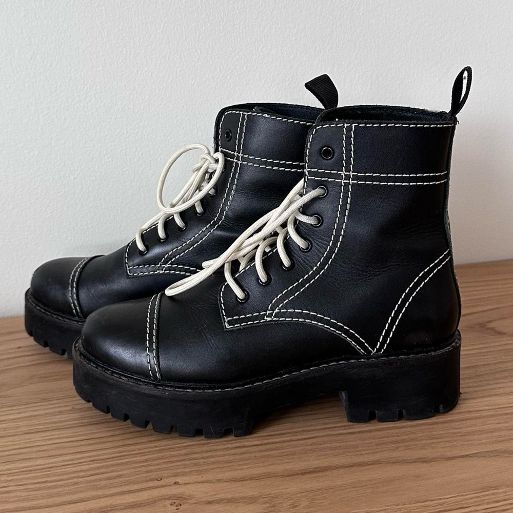 Black lace-up combat boots with white stitching
